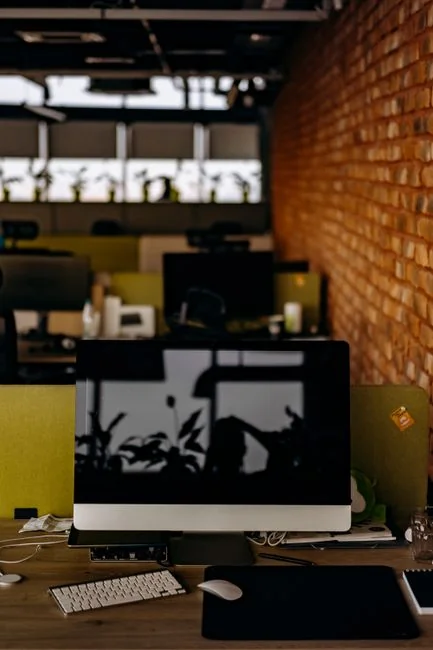 A sleek office desk setup featuring Apple devices: iMac, MacBook, and iPad.